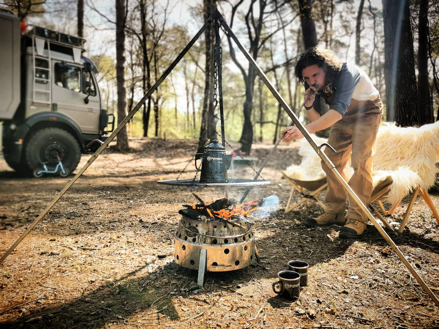 Eine Person kocht Kaffee mit einem Petromax Perkolator auf einem Atago-Grill im Wald