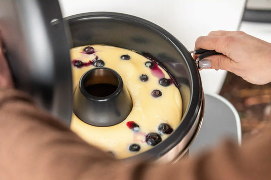 Eine Person bereitet Teig im Dimego Camping Backofen vor