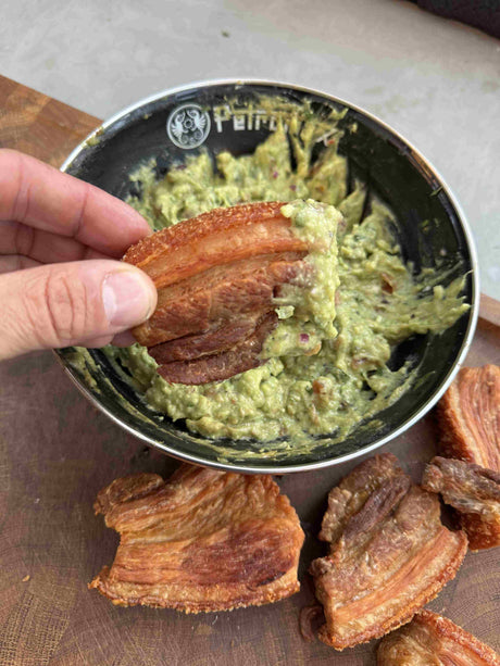 Knusprige Chicharróns aus Schweinebauch mit frischer Guacamole und Limettenspalten aus einer Petromax Emaille Schüssel.