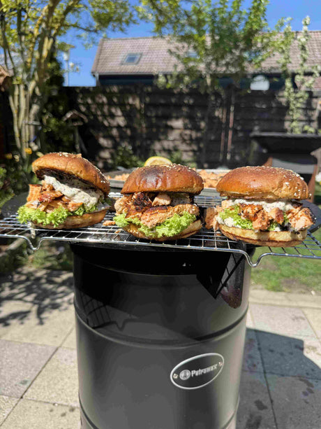 Drei Pulled Lachs Burger mit gegrilltem Lachs, cremiger Senf-Dill-Sauce und frischem Lollo Rosso in einem Brioche Bun auf der Petromax Plancha Grillplatte serviert.