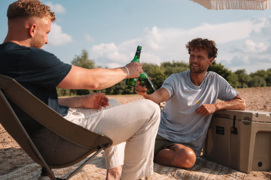 Personen machen ein Picknick am Strand mit einer Kühlbox